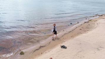 A young woman in a dress runs along the beach Aerial shoot video