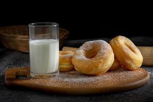 Donuts with sugar on a wooden plate over a dark table background photo