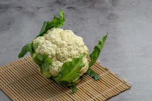 Coliflor fresca prepararse para cocinar sobre mesa gris foto