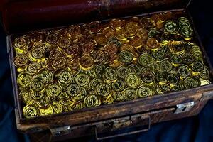 apilamiento de monedas de oro en el cofre del tesoro foto