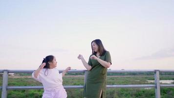 mãe asiática e criança dançando ao ar livre