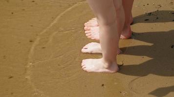 os pés estão na areia perto da água. praia dia ensolarado de verão