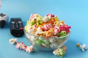 Popcorn and TV remote on blue background photo