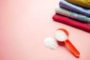 Washing powder in plastic spoon on blue background photo