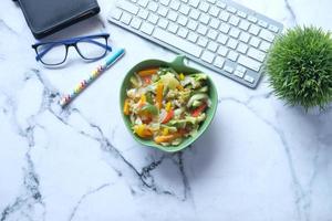 Vista superior del plato de verduras frescas hervidas en el escritorio de oficina