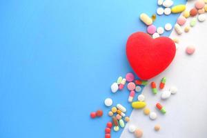 Heart shape symbol and pills on green background photo