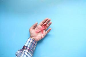 Hand holding red HIV ribbon top down photo