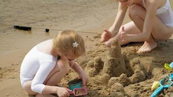 Mom and daughter playing on the beach building a sand castle video