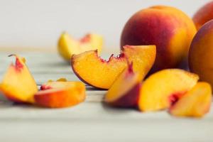 Whole peaches and slices, on white wooden board photo
