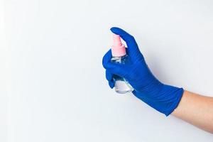 A hand in a blue latex glove holds a disinfectant. The concept of preventive protection against coronavirus.