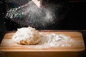 Chef kneads pizza dough on a board photo