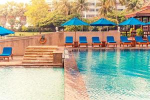 Beautiful umbrella and chair around swimming pool in hotel and resort photo