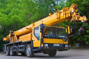 Crane on a road and tower crane in construction site photo