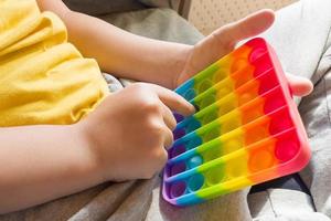 Colorful anti-stress sensory fidget push pop it toy in children's hands