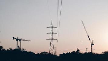 Abstract Industrial background with construction cranes silhouettes over amazing sunset sky photo