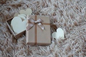 caja de regalo con una cinta y un lazo marrón sobre un fondo de alfombra de lana. enfoque selectivo. foto