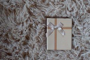 Gift box with a  ribbon and a Brown bow on a Wool carpet background. Selective focus. photo