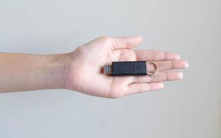 Imagen de primer plano mano sujetando una unidad de memoria USB negra para almacenamiento de datos foto