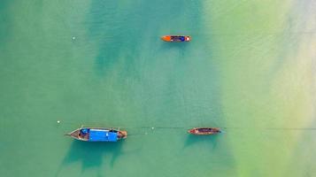 Aerial top view, Fishing boat, Tourist boat floating on a shallow clear sea, Beautiful bright blue water in the ocean photo