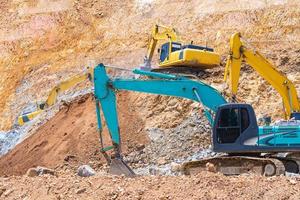 Excavators and stone crushing machine of mining under a blue sky with clouds photo