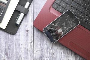 Top view of broken smart phone on laptop on table photo