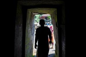 Silhouette of man at the entrance to the Goa Gajah cave in Bali photo