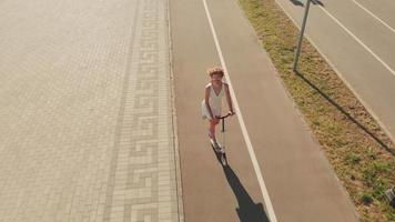 Aerial shot of a woman riding a scooter outdoors in a summer day