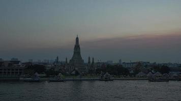 solnedgång tidsfördröjning av wat arun tempel och båttrafik vid chao phraya floden i bangkok, thailand. video