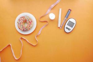 Herramientas de medición de diabetes, insulina y donas en rosa. foto