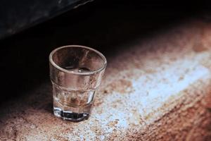 Small empty glass standing alone on concrete surface photo