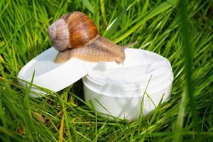 White cream with snail mucin on the green grass in the garden, beautiful skin care photo