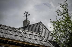 A vintage weather vane on a wooden roof photo