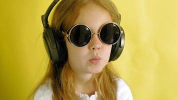 petite fille joyeuse dans les écouteurs sur fond jaune closeup portrait video
