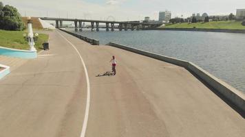 Young woman riding a bicycle outdoors in summer River embankment Friendlily transport Aerial shooting