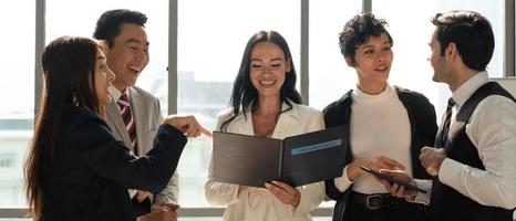 imagen de banner del equipo de negocios internacionales que incluye personas caucásicas y asiáticas de pie junto a la ventana en la oficina y discutiendo sobre el proyecto. diversidad en el concepto de negocio foto