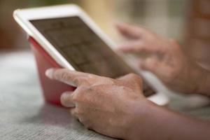 Hombre asiático senior que usa la tableta para reproducir las redes sociales en casa durante el tiempo libre