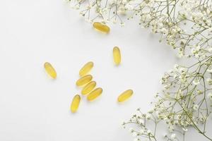 Cod liver oil omega 3 gel capsules isolated on white background. Fish oil gel capsules with a bouquet of spring flowers. Vitamins