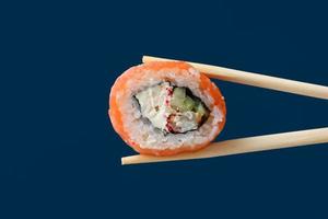 Cerrar rollo de sushi de salmón fresco con palillos de madera