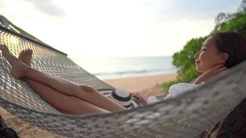 aziatische vrouw geniet van een prachtig strand op een hangmat