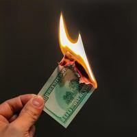 The hand holds a burning hundred dollars. Illustration of the financial crisis and loss of money and capital. photo