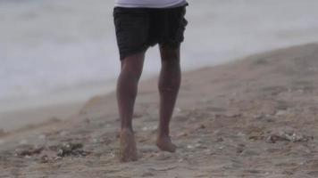 los pies descalzos de un joven corriendo en la playa.