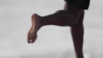 los pies descalzos de un joven corriendo en la playa.