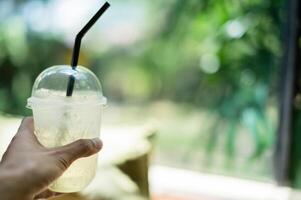 Hand holding a glass of water, the taste of lemon juice mixed with honey. photo