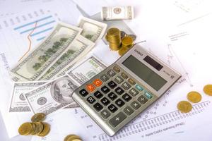 los inversores calculan las ganancias y las tasas de interés con una calculadora y tienen una pequeña cantidad de dinero. foto
