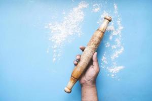 Holding rolling pin on blue background, top view photo