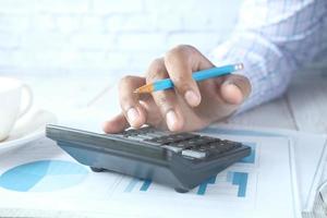 Close up of man hand using calculator with financial data on table photo