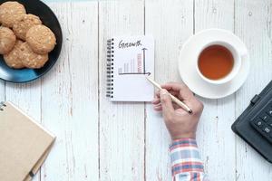 Tabla de crecimiento escritos a mano en el bloc de notas en el escritorio de oficina foto