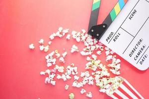 Movie clapper board and popcorn on red background photo