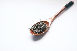 green tea dry leafs on spoon on white photo