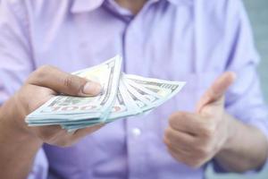 Close up of man holding us dollar and showing thumbs up photo